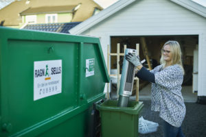 Kvinne som kaster elavfall i egen søppeldunk vedsiden av container.